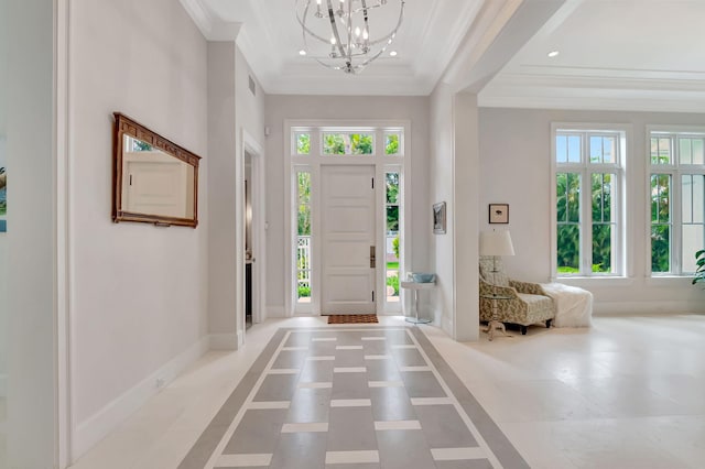 foyer with a raised ceiling, an inviting chandelier, plenty of natural light, and ornamental molding