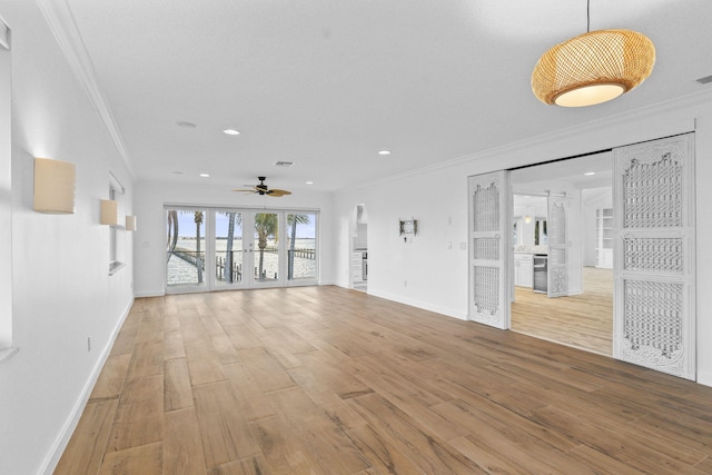 unfurnished living room with hardwood / wood-style floors, ceiling fan, ornamental molding, and french doors