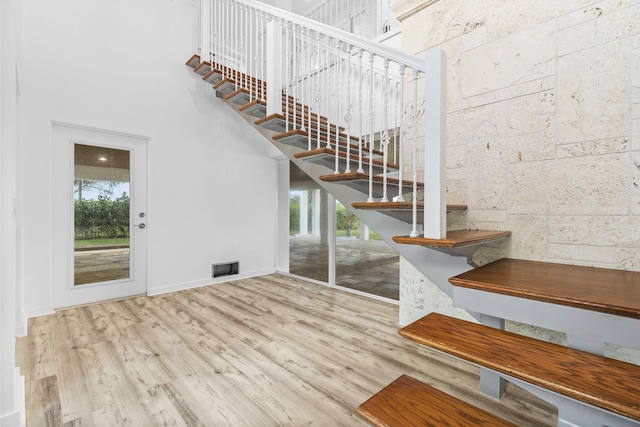 stairs with hardwood / wood-style flooring, a high ceiling, and a wealth of natural light