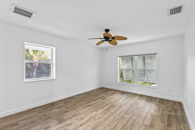 unfurnished room with a textured ceiling, light wood-type flooring, and ceiling fan