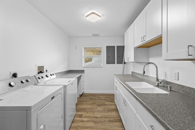 clothes washing area with sink, cabinets, dark wood-type flooring, a textured ceiling, and washer and clothes dryer