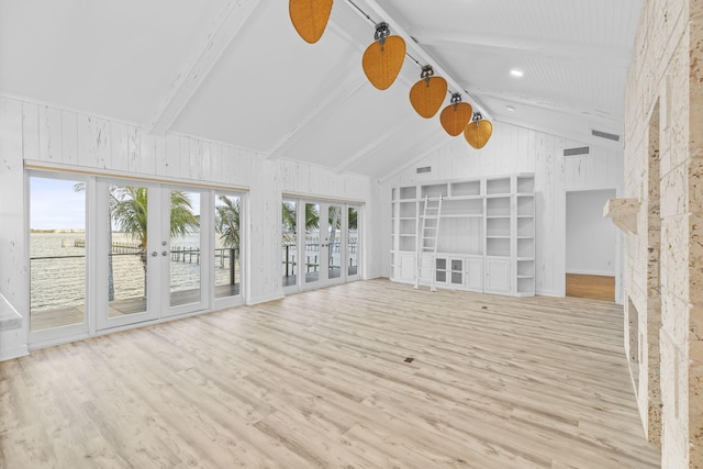 unfurnished living room with light wood-type flooring, french doors, lofted ceiling with beams, and wooden walls