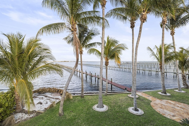 view of dock with a yard and a water view