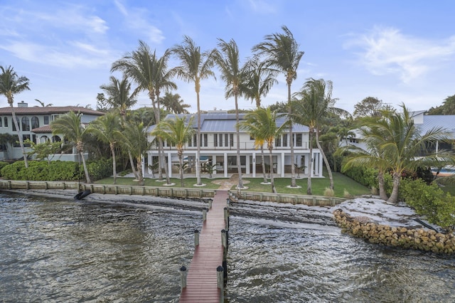 dock area featuring a lawn, a balcony, and a water view