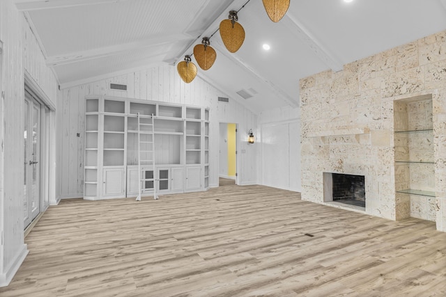 unfurnished living room featuring a fireplace, beam ceiling, and light hardwood / wood-style floors