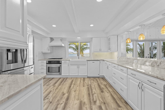 kitchen with white cabinets, appliances with stainless steel finishes, light wood-type flooring, and custom exhaust hood