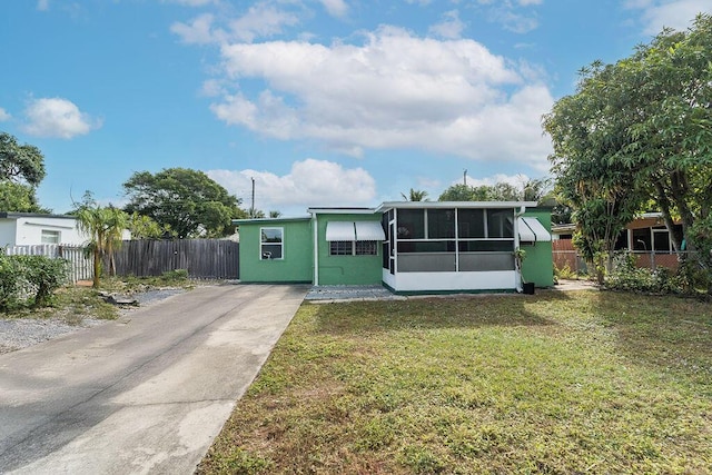 view of front of house with a sunroom and a front lawn