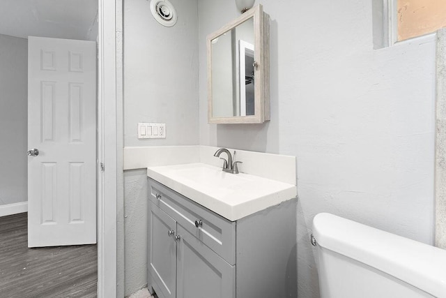 bathroom with hardwood / wood-style flooring, vanity, and toilet