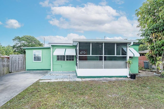 back of property with a sunroom and a yard