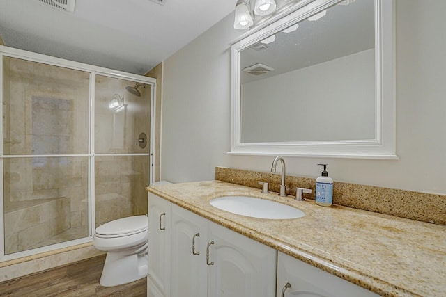 bathroom with toilet, vanity, a shower with door, and hardwood / wood-style flooring