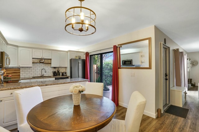 dining space with dark hardwood / wood-style flooring, a chandelier, and sink