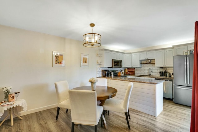 dining room featuring an inviting chandelier, light hardwood / wood-style floors, and sink