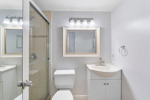 bathroom featuring vanity, a shower with shower door, and toilet