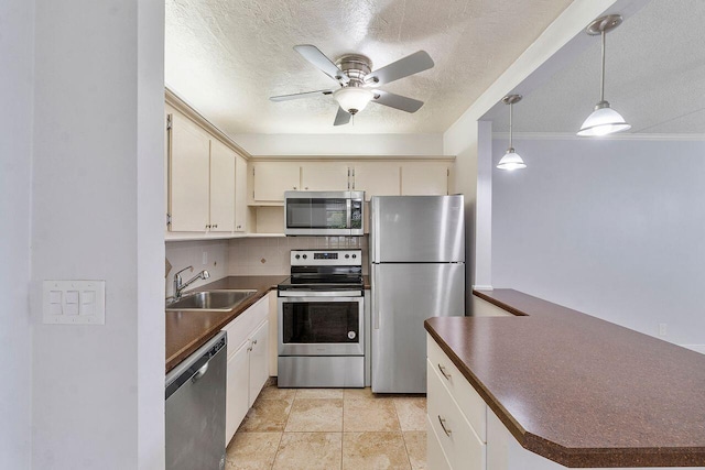 kitchen with appliances with stainless steel finishes, a textured ceiling, decorative light fixtures, and sink