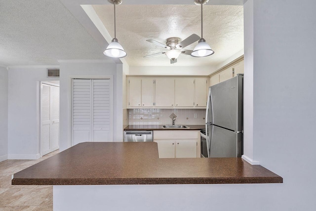 kitchen featuring sink, kitchen peninsula, pendant lighting, decorative backsplash, and appliances with stainless steel finishes