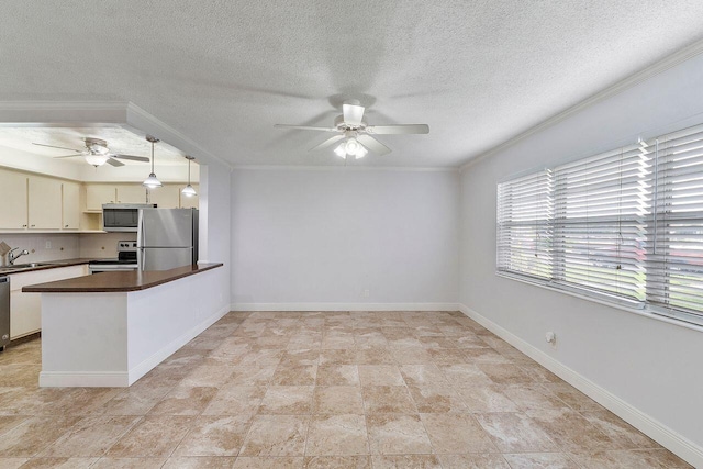 kitchen with pendant lighting, sink, appliances with stainless steel finishes, cream cabinetry, and kitchen peninsula