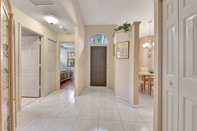 entrance foyer featuring a notable chandelier, light tile patterned floors, and a textured ceiling