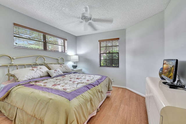 bedroom featuring multiple windows, ceiling fan, light hardwood / wood-style flooring, and a textured ceiling