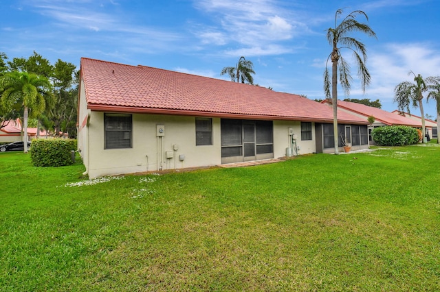 rear view of house featuring a lawn and a sunroom