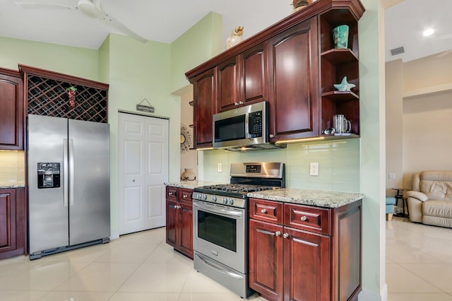 kitchen featuring light stone countertops, ceiling fan, decorative backsplash, light tile patterned floors, and appliances with stainless steel finishes