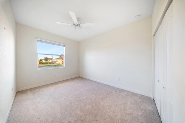 unfurnished bedroom with light carpet, a closet, and ceiling fan