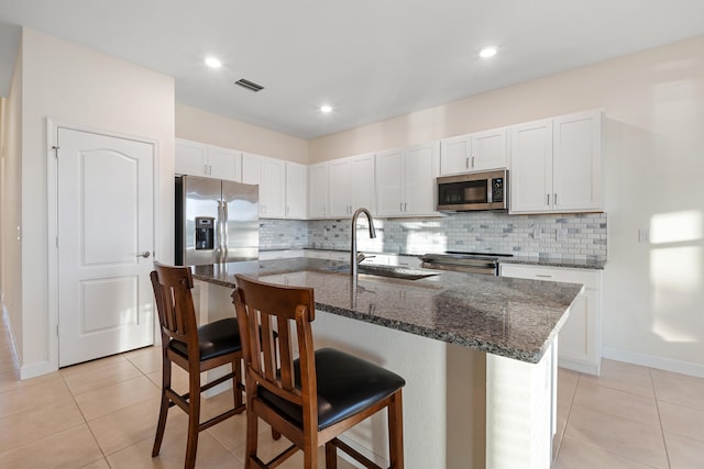 kitchen featuring a breakfast bar, white cabinets, sink, an island with sink, and stainless steel appliances