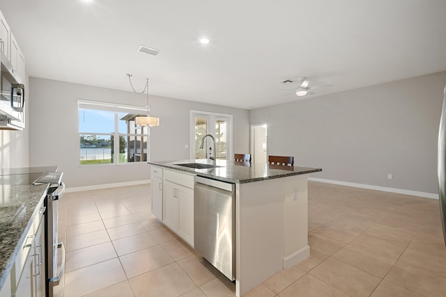 kitchen with appliances with stainless steel finishes, white cabinetry, a kitchen island with sink, and sink