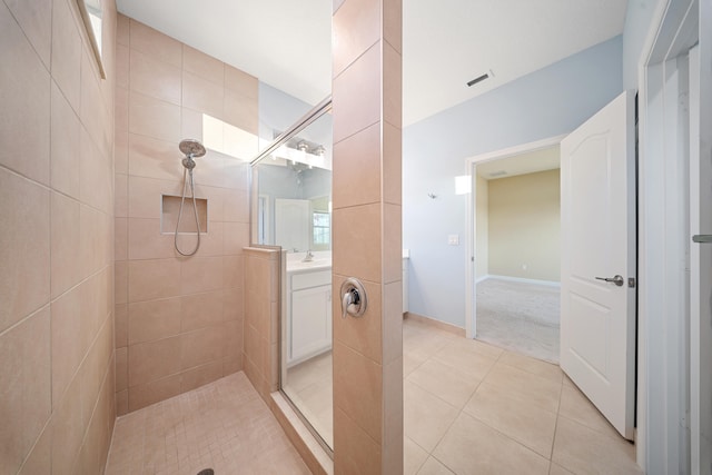 bathroom with tiled shower, vanity, and tile patterned flooring