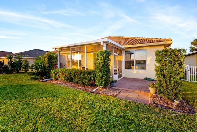 rear view of house featuring a patio area, a sunroom, and a yard