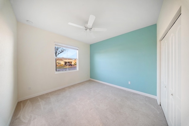 unfurnished bedroom featuring ceiling fan, a closet, and light carpet