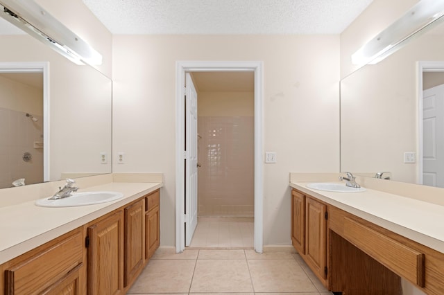 bathroom with a tile shower, vanity, tile patterned floors, and a textured ceiling