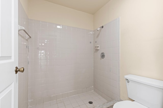 bathroom featuring a tile shower and toilet