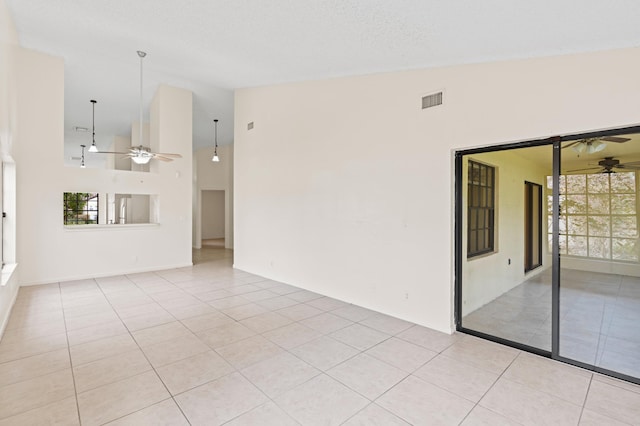 unfurnished room with light tile patterned flooring, ceiling fan, high vaulted ceiling, and a textured ceiling