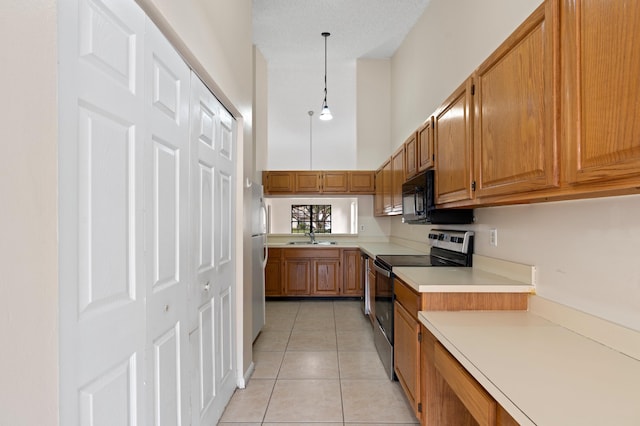 kitchen with light tile patterned floors, sink, a towering ceiling, stainless steel electric range oven, and decorative light fixtures