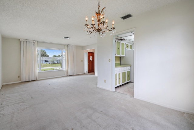 unfurnished room with light colored carpet, a textured ceiling, and an inviting chandelier