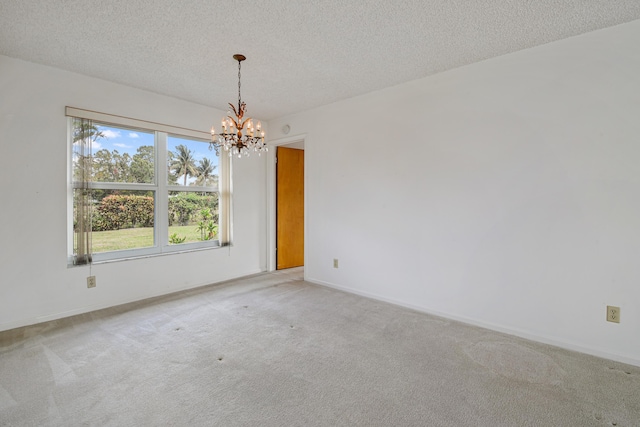 carpeted empty room with a chandelier and a textured ceiling