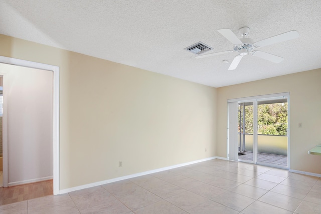 spare room with ceiling fan, light tile patterned floors, and a textured ceiling