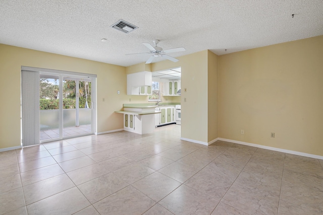 unfurnished living room with light tile patterned floors, a textured ceiling, ceiling fan, and sink