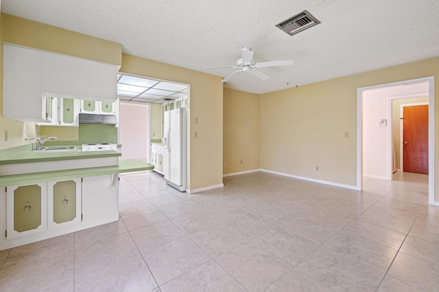 kitchen with sink, ceiling fan, white fridge with ice dispenser, a textured ceiling, and white cabinetry