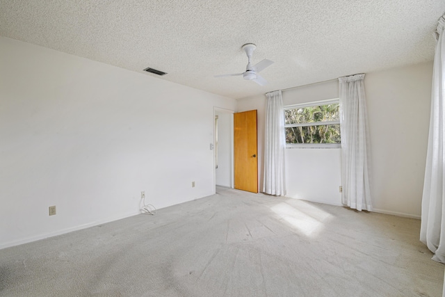 spare room with ceiling fan, a textured ceiling, and light carpet