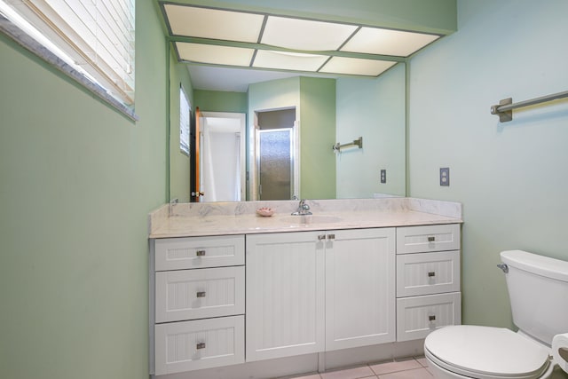 bathroom featuring tile patterned flooring, vanity, toilet, and walk in shower