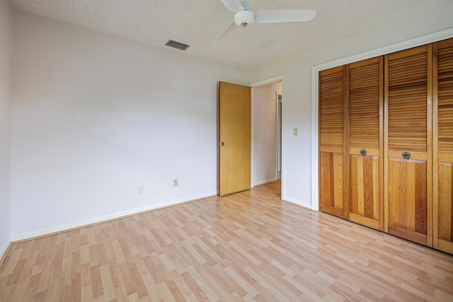 unfurnished bedroom featuring a textured ceiling, light wood-type flooring, a closet, and ceiling fan