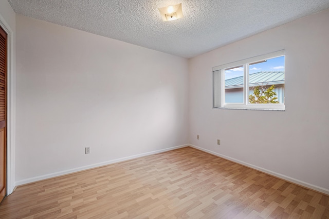 unfurnished room featuring light wood-type flooring and a textured ceiling