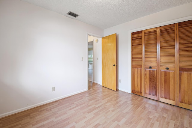 unfurnished bedroom with a closet, a textured ceiling, and light hardwood / wood-style flooring