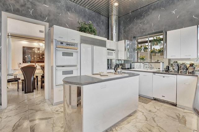 kitchen featuring white appliances, sink, white cabinets, a high ceiling, and a center island