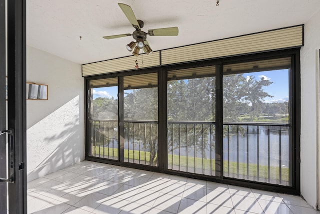 unfurnished sunroom featuring a water view and a ceiling fan