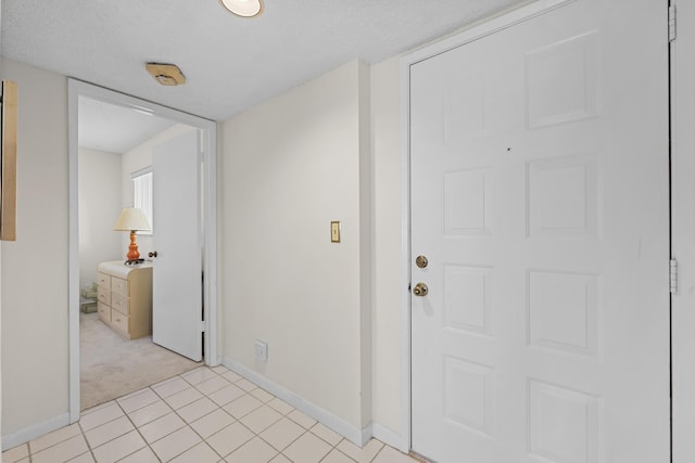 hall featuring light colored carpet and a textured ceiling