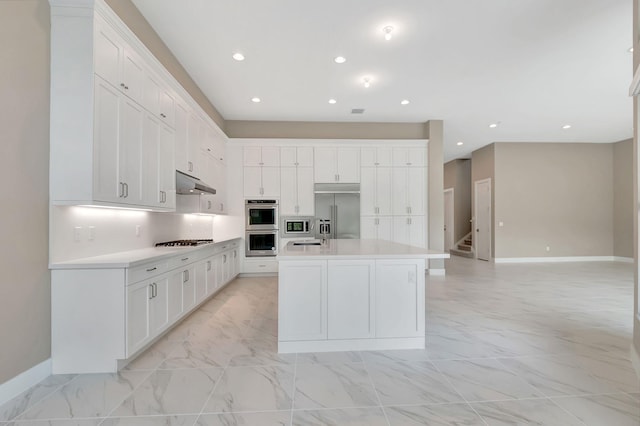 kitchen with a center island with sink, sink, white cabinets, and stainless steel appliances