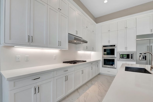 kitchen featuring built in appliances, white cabinetry, and sink