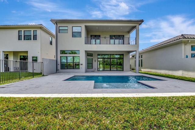 rear view of house with a patio area, a balcony, a fenced in pool, and a yard